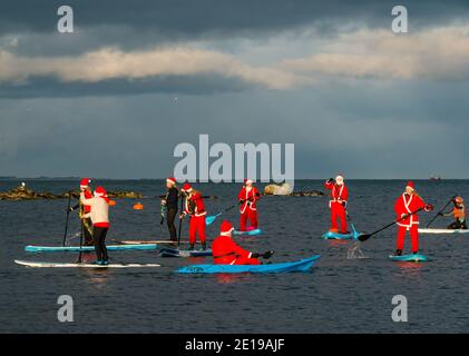 Événement caritatif communautaire : paddle Boarders en costumes de Santa, North Berwick, East Lothian, Écosse, Royaume-Uni Banque D'Images