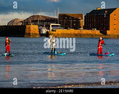 Événement caritatif communautaire : paddle Boarders en costumes de Santa, North Berwick, East Lothian, Écosse, Royaume-Uni Banque D'Images