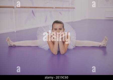 Mignonne jeune ballerine heureux faisant des fentes, souriant à l'appareil photo. Charmante petite fille portant le léopard et le tutu, s'étirant avant sa leçon de ballet à Banque D'Images