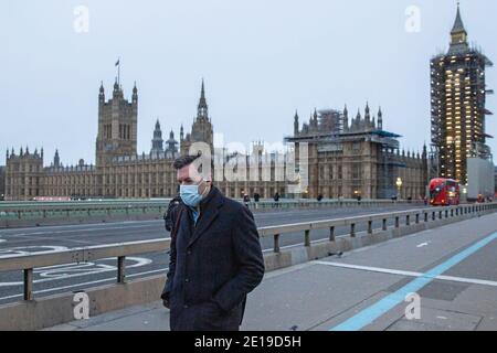 Un homme masqué traverse un paisible pont de Westminster Le matin du 5 janvier 2021 comme le Le verrouillage national entre en vigueur Banque D'Images