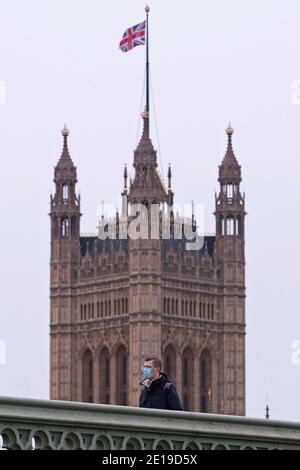 Un homme masqué traverse le pont de Westminster le matin Du 5 janvier 2021 comme le verrouillage national prend effet Banque D'Images