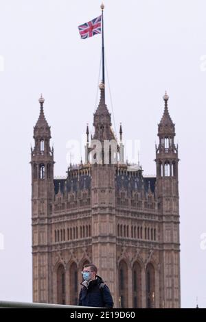 Un homme masqué traverse le pont de Westminster le matin Du 5 janvier 2021 comme le verrouillage national prend effet Banque D'Images