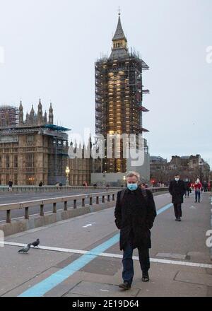 Un homme masqué traverse un paisible pont de Westminster Centre de Londres le matin du 5 janvier 2021 comme le verrouillage national prend effet Banque D'Images