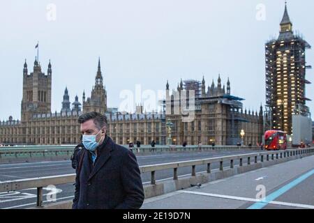 Un homme masqué traverse un paisible pont de Westminster, dans le centre de Londres, le matin du 5 janvier 2021, alors que le verrouillage national prend effet Banque D'Images