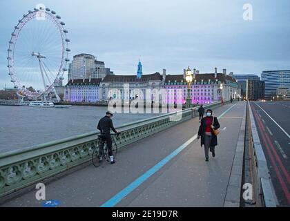 Une femme masquée traverse un paisible pont de Westminster, dans le centre de Londres, le matin du 5 janvier 2021, alors que le verrouillage national prend effet Banque D'Images