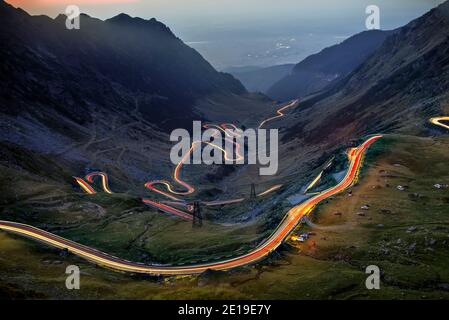 La route courbe de Transfagarasan vue avec des feux de route de voiture à l'heure bleue. Photo prise le 31 août 2019, comté de Sibiu, Roumanie. Banque D'Images