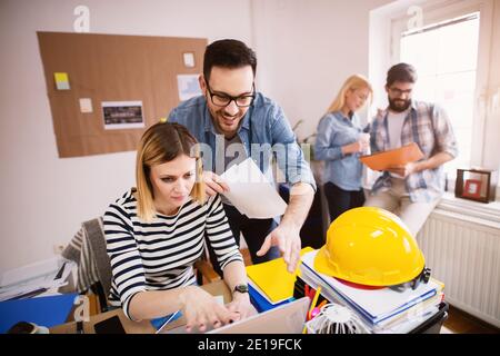 Groupe de jeunes ingénieurs joyeux et séduisants travaillant ensemble dans un bureau lumineux. Banque D'Images