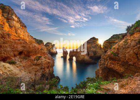 Le lever du soleil se fait au-dessus des formations rocheuses du Ponte de Piedade près de Lagos, dans la région de l'Algarve, au Portugal. Banque D'Images