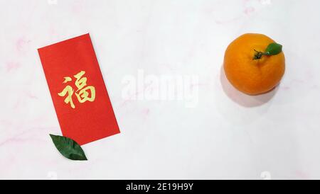 Un orange mandarin avec un ang pow rouge (un cadeau monétaire offert lors d'occasions spéciales dans la culture chinoise, en particulier le nouvel an chinois). Banque D'Images