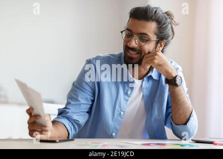 Styliste d'intérieur homme arabe gai tenant des échantillons de nuances de couleur, en vérifiant la nouvelle palette Banque D'Images