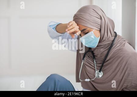 Médecin musulman stressé dans un masque facial touchant son front Banque D'Images