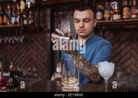 Barman professionnel préparant une boisson. Beau barman homme mélangeant de la liqueur Banque D'Images