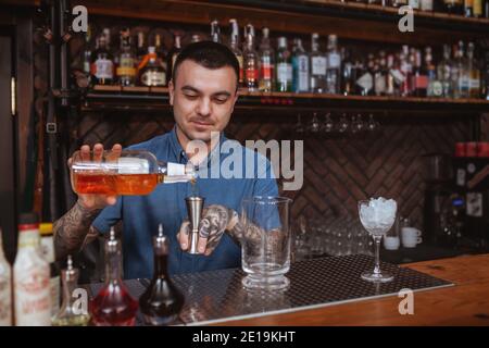 Beau barman gai appréciant de travailler à son bar, en faisant des cocktails pour les clients Banque D'Images
