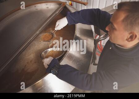 Vue de dessus prise de vue d'un homme travaillant à l'usine de bière, examinant la fermentation de la bière dans un réservoir Banque D'Images