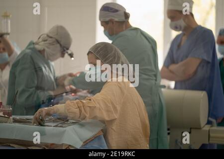 Les médecins et les infirmières effectuent une opération dans une salle d'opération. Équipe de travailleurs médicaux portant des masques et des uniformes. Hôpital de la ville. Mai 2020 Banque D'Images