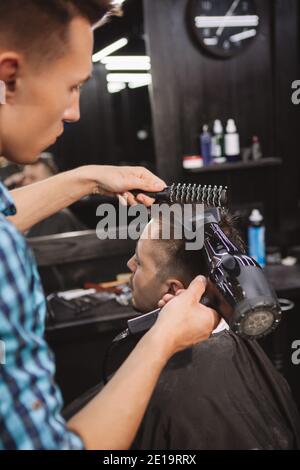 Plan vertical d'un homme dont les cheveux ont été séchés par un barbier professionnel. Plan court d'un coiffeur soufflent sécher les cheveux d'un client mâle après givi Banque D'Images