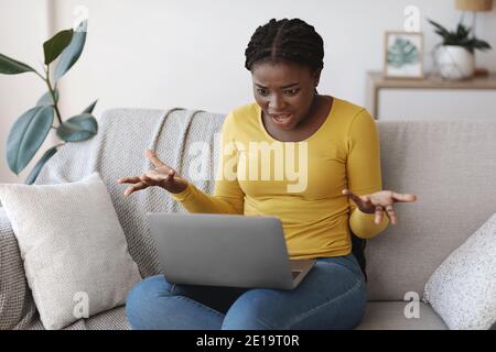 Frustrée femme afro-américaine souffrant de problèmes avec ordinateur portable à Accueil Banque D'Images