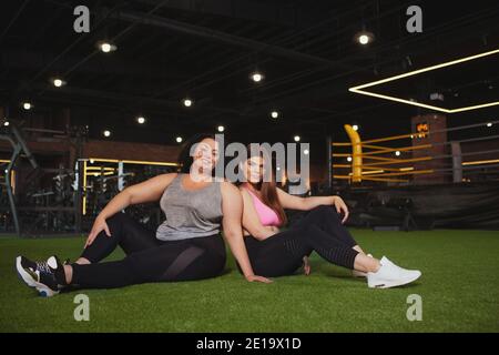 Deux belles femmes de forme physique bonne santé plus taille se reposant à la salle de gym après l'exercice, copier l'espace. Des amis en surpoids se détendent après l'entraînement Banque D'Images