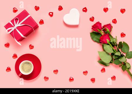 Bouquet de roses rouges, boîte-cadeau, tasse de café et coeurs sur fond rose. Fête de la mère, de la femme ou de la Saint-Valentin. Concept d'amour et de datation Banque D'Images