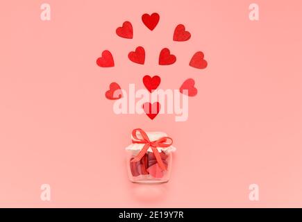 Coeurs en bois rouge dans un pot avec nœud papillon sur fond rose pastel. Composition romantique de coeur pour la Saint-Valentin ou carte de fête des mères Banque D'Images