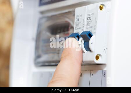 La main pointe vers un fusible du wattmètre. L'homme désactive les fusibles de courant, le concept de sécurité de la suppression de puissance et la protection de e Banque D'Images