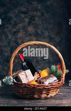 Bouteille de vin rouge dans le panier cadeau de Noël. Vin chaud accompagné d'oranges, de tasses et de décorations en sapin dans une boîte. Vue de dessus Banque D'Images