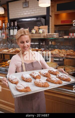 Portrait vertical d'un bac de transport femelle plein de croissants frais Banque D'Images