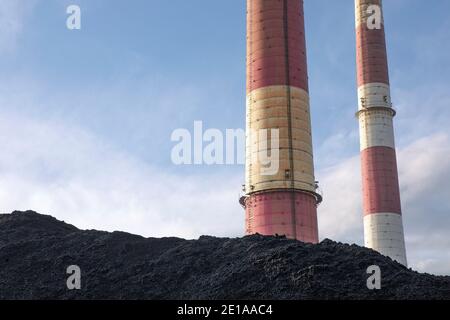 Tas de charbon, charbon noir naturel avec cheminées industrielles. Arrière-plan industriel. Réchauffement de la planète, émissions de CO2, questions énergétiques liées au charbon, énergie issue du fu fossile Banque D'Images