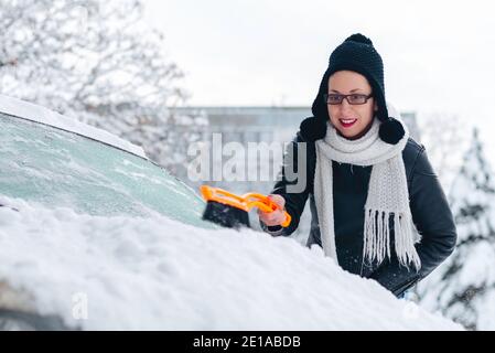 Fille déneigement de la voiture et appréciant la journée d'hiver activité Banque D'Images