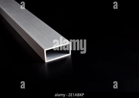Photo du profil de tube en acier aluminium pour la fabrication de fenêtres et de portes. Constructions en aluminium sur fond de surface sombre. Banque D'Images