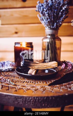 Bois de Palo Santo connu sous le nom de bâton de bois Saint aromatique huileux couvant sur plaque dans la maison salle de séjour nettoyage négatif concept d'énergie. Style bohémien. Banque D'Images