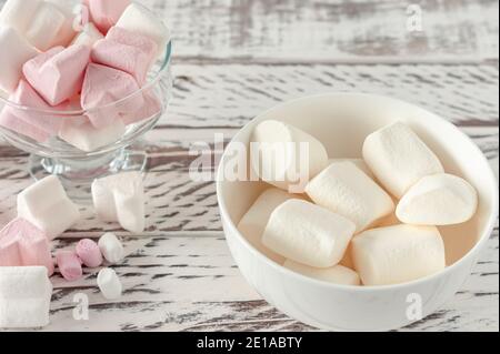 Assortiment de guimauves roses et blanches dans des tasses en verre sur fond de bois. Guimauve en forme de coeur pour chocolat chaud ou cacao. Banque D'Images