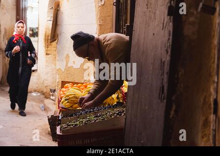 Fez, Maroc - novembre 27 2015 : un vendeur de rue a tendance à exposer ses fruits et légumes sur un marché de produits frais dans la médina de Fès, au Maroc. Banque D'Images