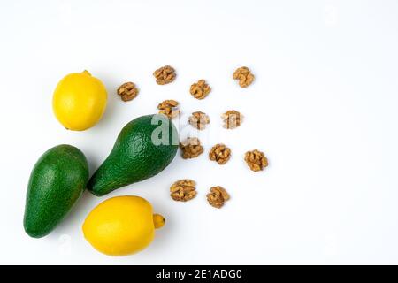 Avocats, citrons et noix sur fond blanc. Banque D'Images