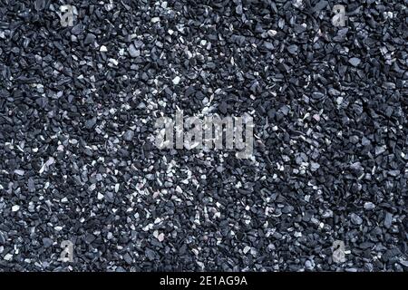 Texture sable noir. Photographie macro plein format d'une surface de sable sombre rugueuse. Arrière-plan de motif abstrait. Elément de conception en gros plan. Vue de dessus. Banque D'Images