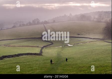 Marcheurs dans un après-midi d'hiver brumeux dans le parc national de Yorkshire Dales, près d'Austwick, Royaume-Uni. Banque D'Images