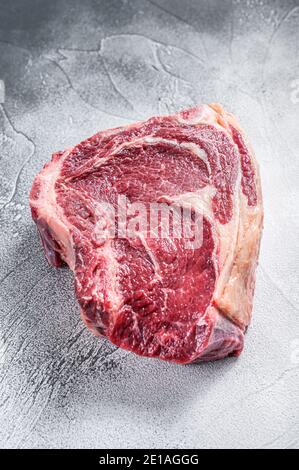 Un steak de cowboy brut ou un œil de côtes sur l'os. Bœuf en marbre. Arrière-plan gris. Vue de dessus Banque D'Images