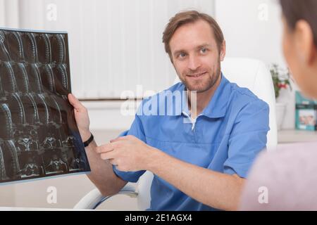 Un médecin de sexe masculin mature qui parle à son patient, lui montrant son IRM. Médecin généraliste expliquant l'IRM à un patient Banque D'Images