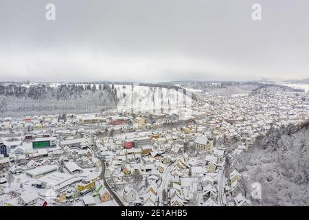 Une aérienne d'hiver enneigée avec vue sur une ville couverte de neige blanche entourée de collines. Banque D'Images