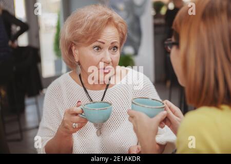 Gros plan d'une femme âgée qui a l'air choquée, recevant des nouvelles de sa fille adulte. La mère âgée a l'air surprise, parlant à sa fille Banque D'Images