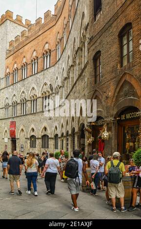 Personnes et touristes devant le palais médiéval de Palazzo Chigi-Saracini, dans le centre historique de Sienne (site classé au patrimoine mondial de l'UNESCO), Toscane, Italie Banque D'Images