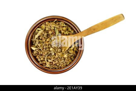 Épice de basilic naturel séché dans un bol en céramique et une cuillère en bois (Ocimum basilicum). Pile d'assaisonnement au basilic séché isolée. Banque D'Images