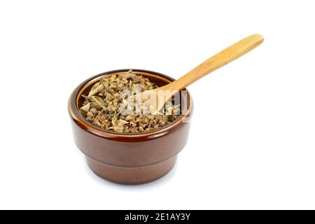 Épice de basilic naturel séché dans un bol en céramique et une cuillère en bois (Ocimum basilicum). Pile d'assaisonnement au basilic séché isolée. Banque D'Images