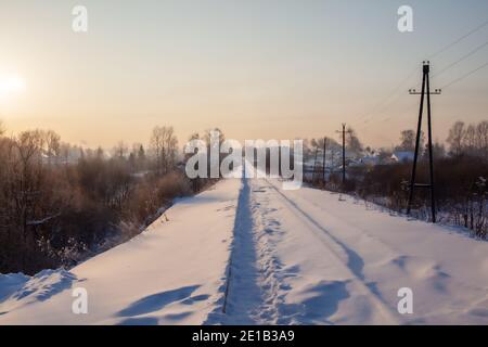 Un chemin de fer recouvert de neige et un chemin de fer trodden par les gens qui le font en hiver. Beaucoup de neige. Rails de fer une voie pour un train dans la direction de la cargaison couverte wi Banque D'Images