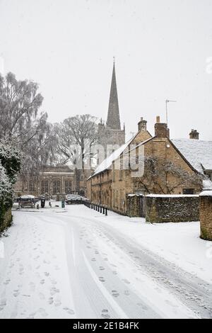 Les grandes Almshres et l'église Saint-Jean-Baptiste le long de la voie de l'église dans la neige de décembre. Burford, Cotswolds, Oxfordshire, Angleterre Banque D'Images