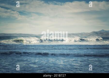 Paysage marin pittoresque. Vagues orageux, montagnes et ciel nuageux en arrière-plan, Californie Banque D'Images