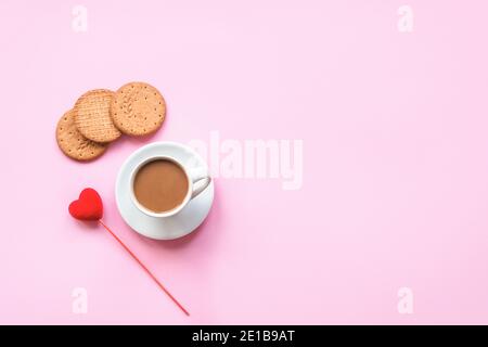 Une tasse de café, des biscuits et un cœur rouge sur fond rose. Concept d'amour, Saint Valentin. Vue de dessus, plat, espace de copie. Banque D'Images
