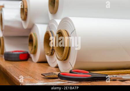 Des rouleaux blancs de film PVC sont sur la table dans l'atelier pour la production de plafonds extensibles. Production de plafonds extensibles. Mise au point sélective Banque D'Images