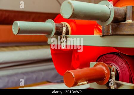 Rouleaux de film PVC rouge vif dans l'atelier pour la production de gros plans de plafonds extensibles. Production de plafonds extensibles. Mise au point sélective Banque D'Images