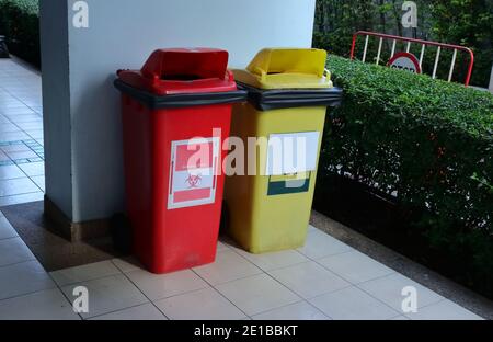 Fermer le bac à déchets biologiques dangereux à côté du bac de recyclage jaune contre le bleu mur Banque D'Images